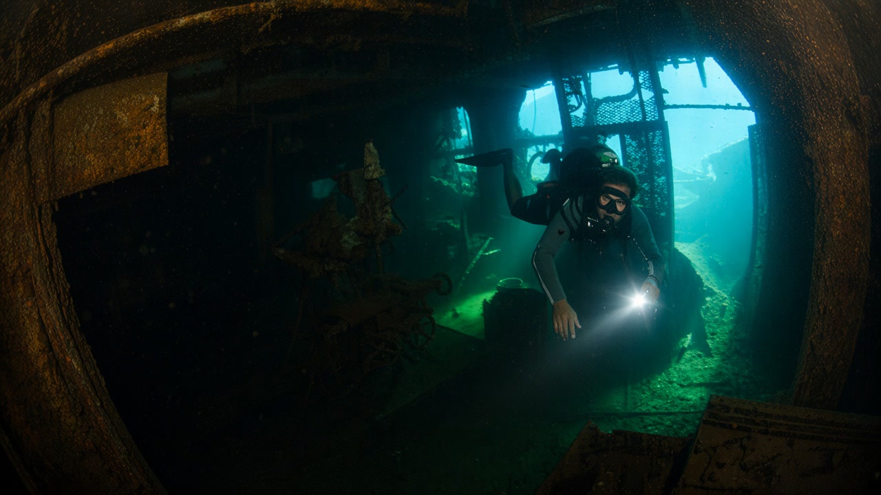 Diver with a torch inside the SS Thistlegorm wreck
